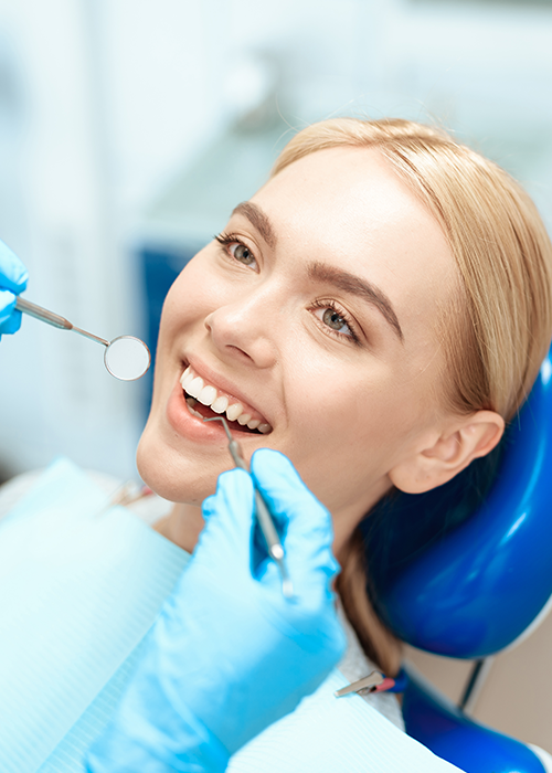 A woman smiling with a dental mirror near the teeth.